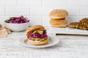 chicken shawarma burger with a bun and slaw on a plate.