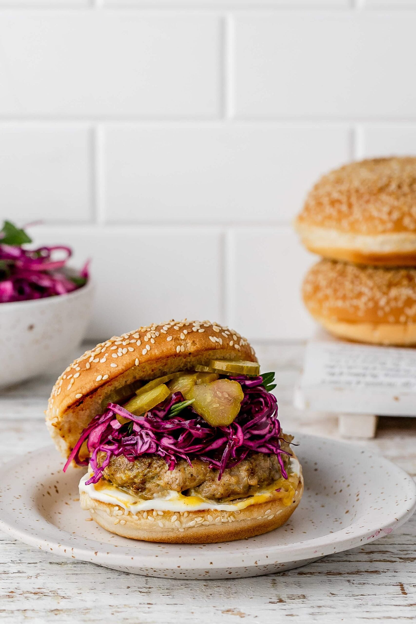 chicken shawarma burger with a bun and slaw on a plate. 