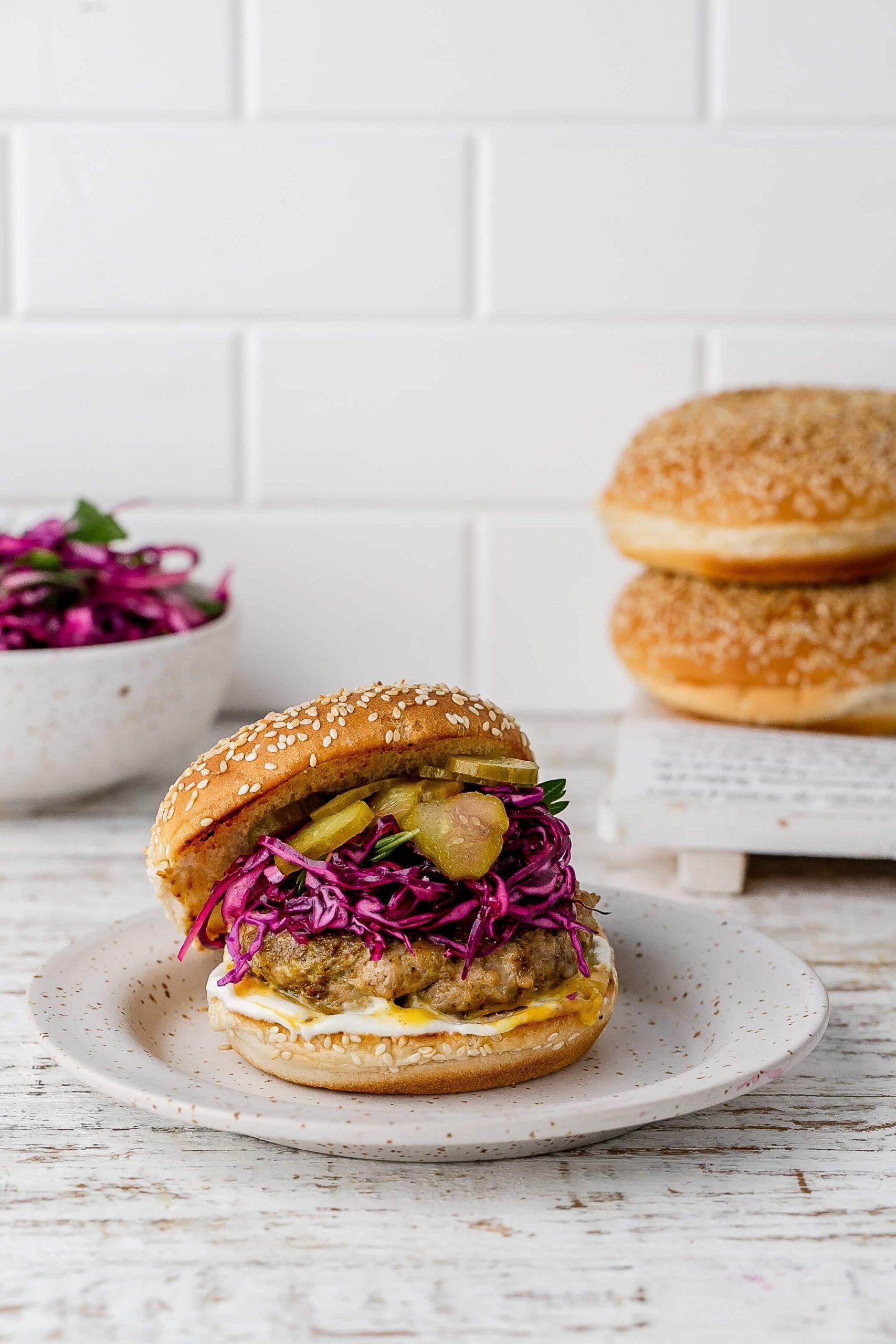 chicken shawarma burger with a bun and slaw on a plate. 