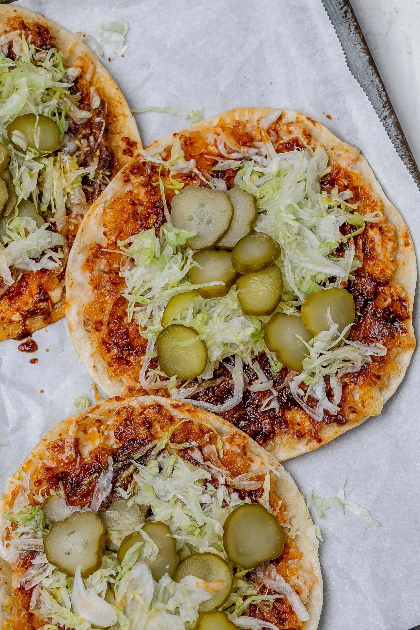 smashed Nashville hot chicken tacos on a baking sheet with toppings.