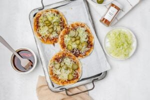 smashed Nashville hot chicken tacos on a baking sheet with toppings.