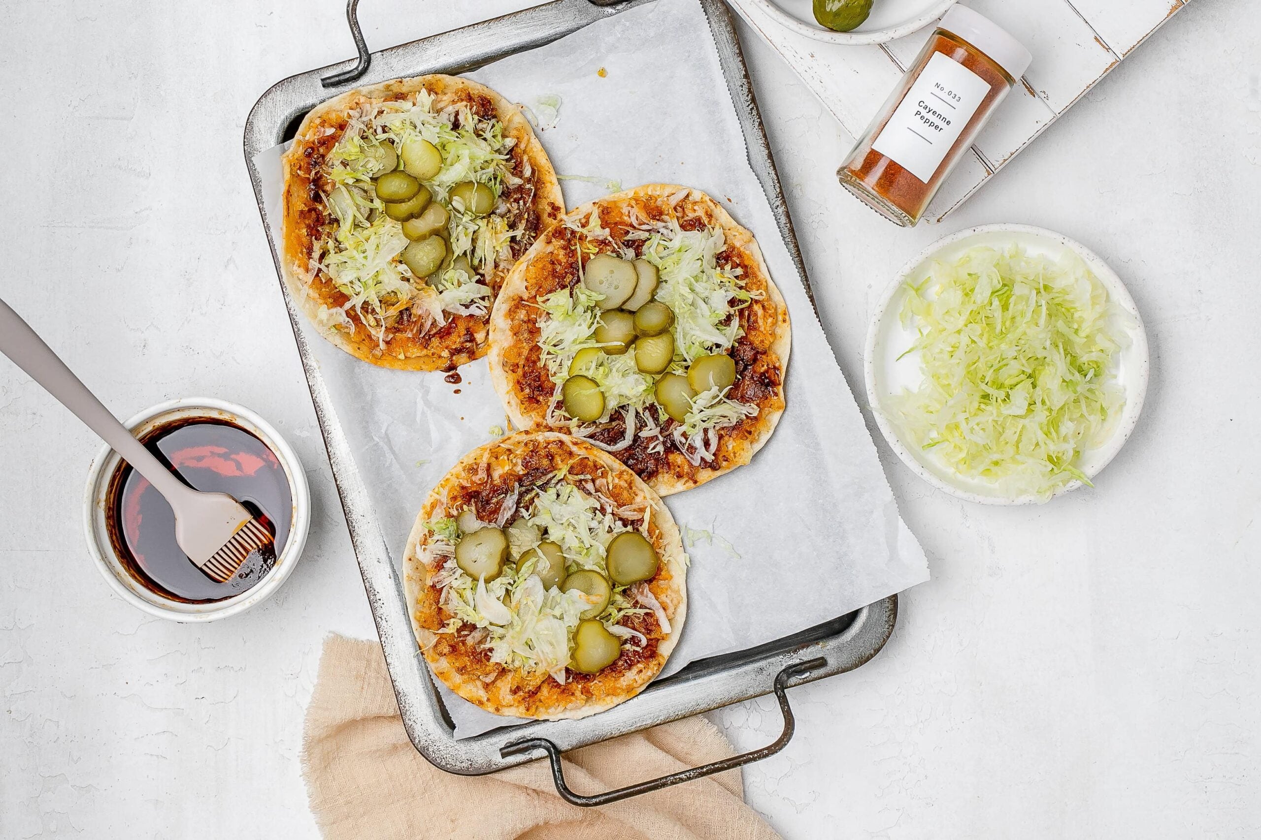 smashed Nashville hot chicken tacos on a baking sheet with toppings.