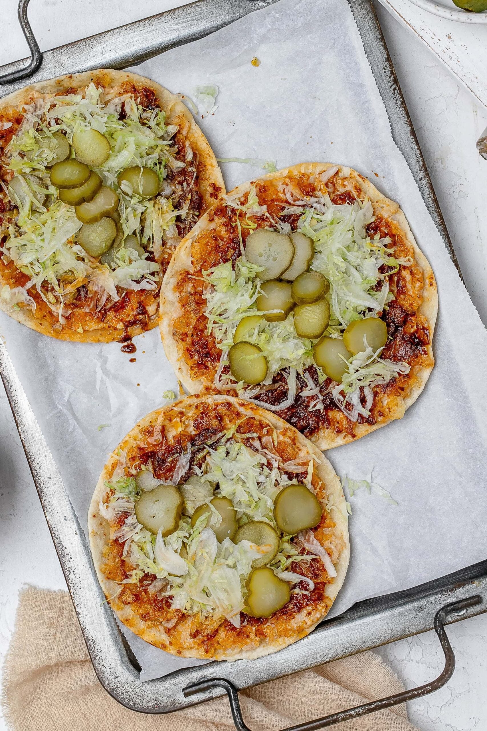 smashed Nashville hot chicken tacos on a baking sheet with toppings.
