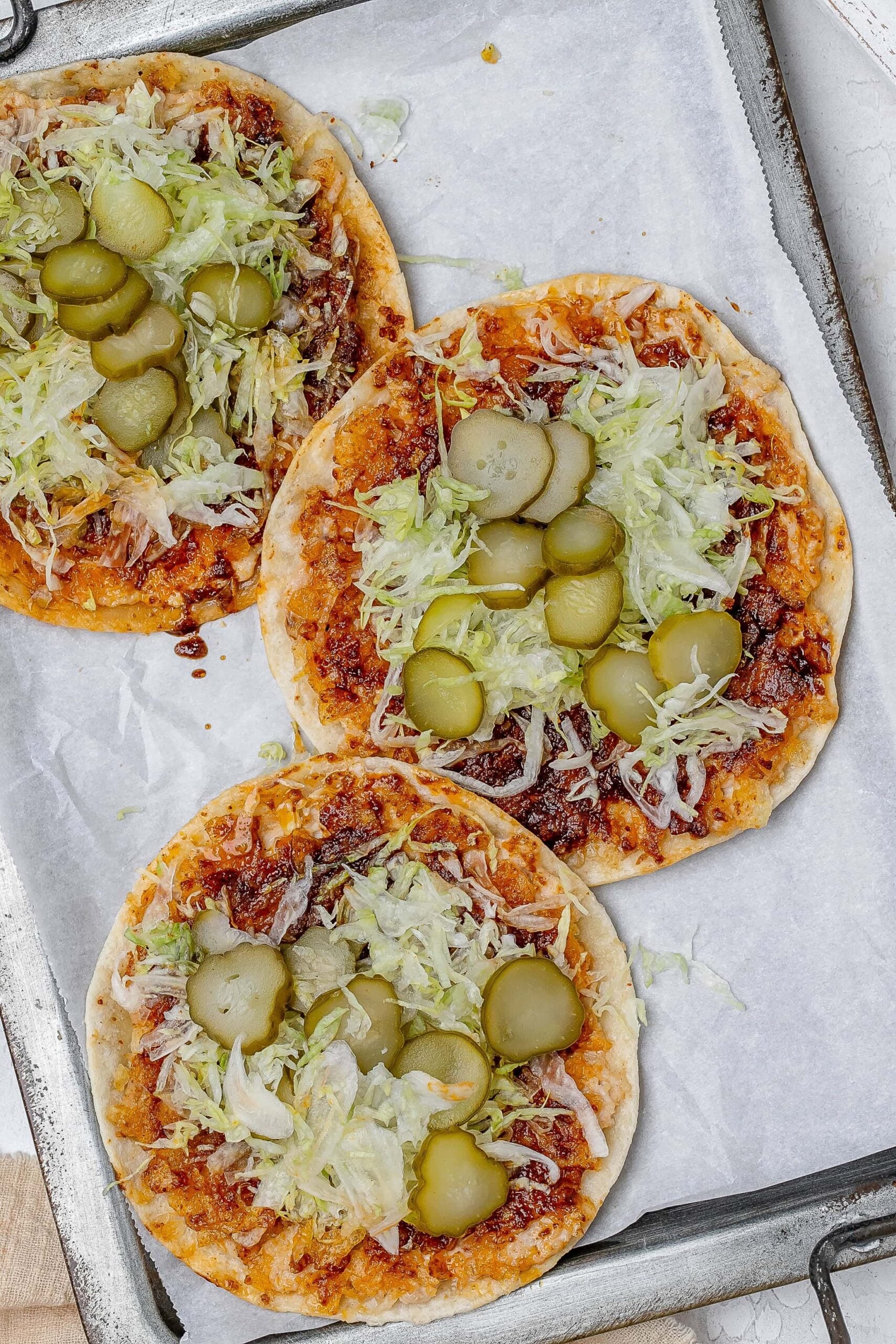 smashed Nashville hot chicken tacos on a baking sheet with toppings.
