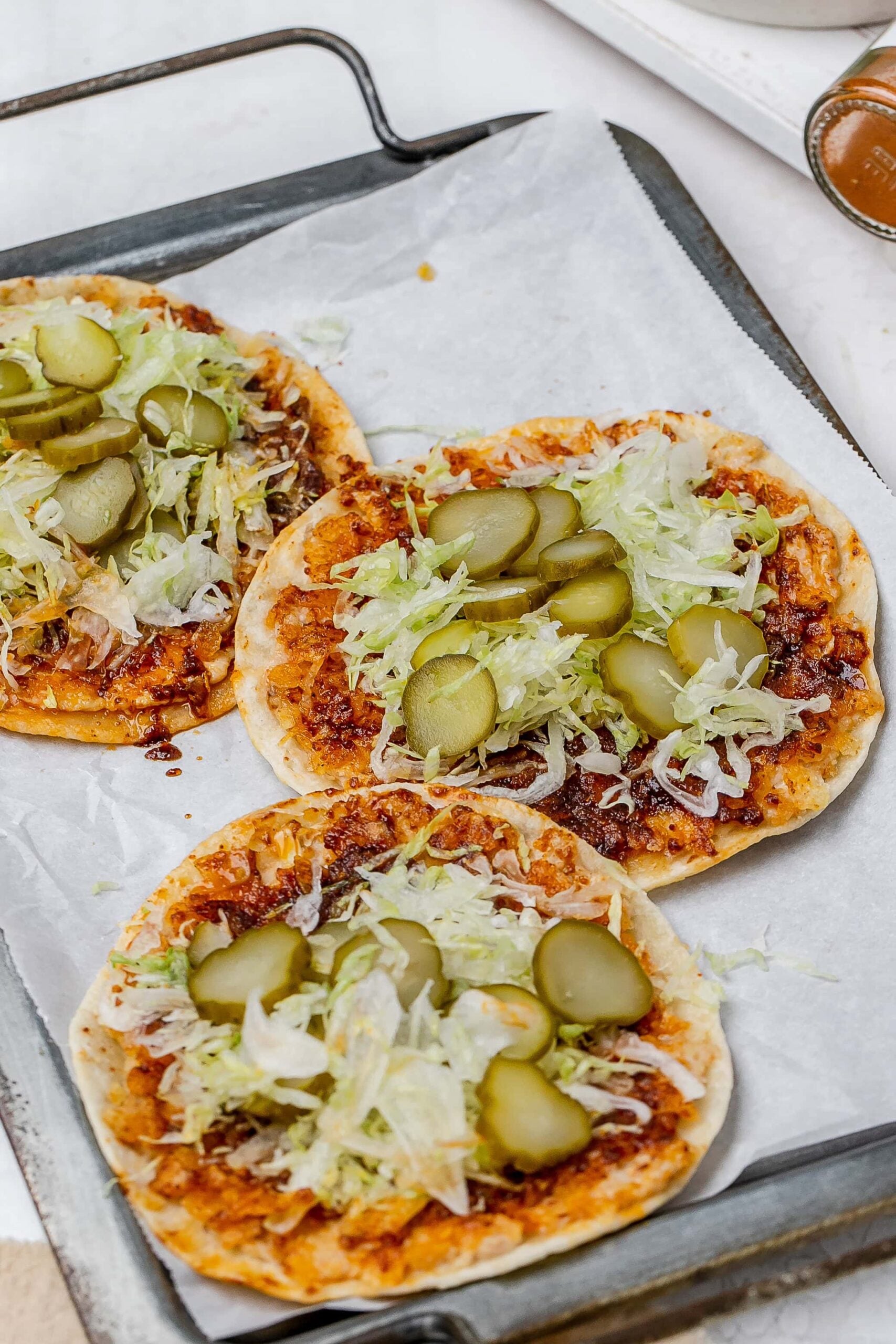 smashed Nashville hot chicken tacos on a baking sheet with toppings.