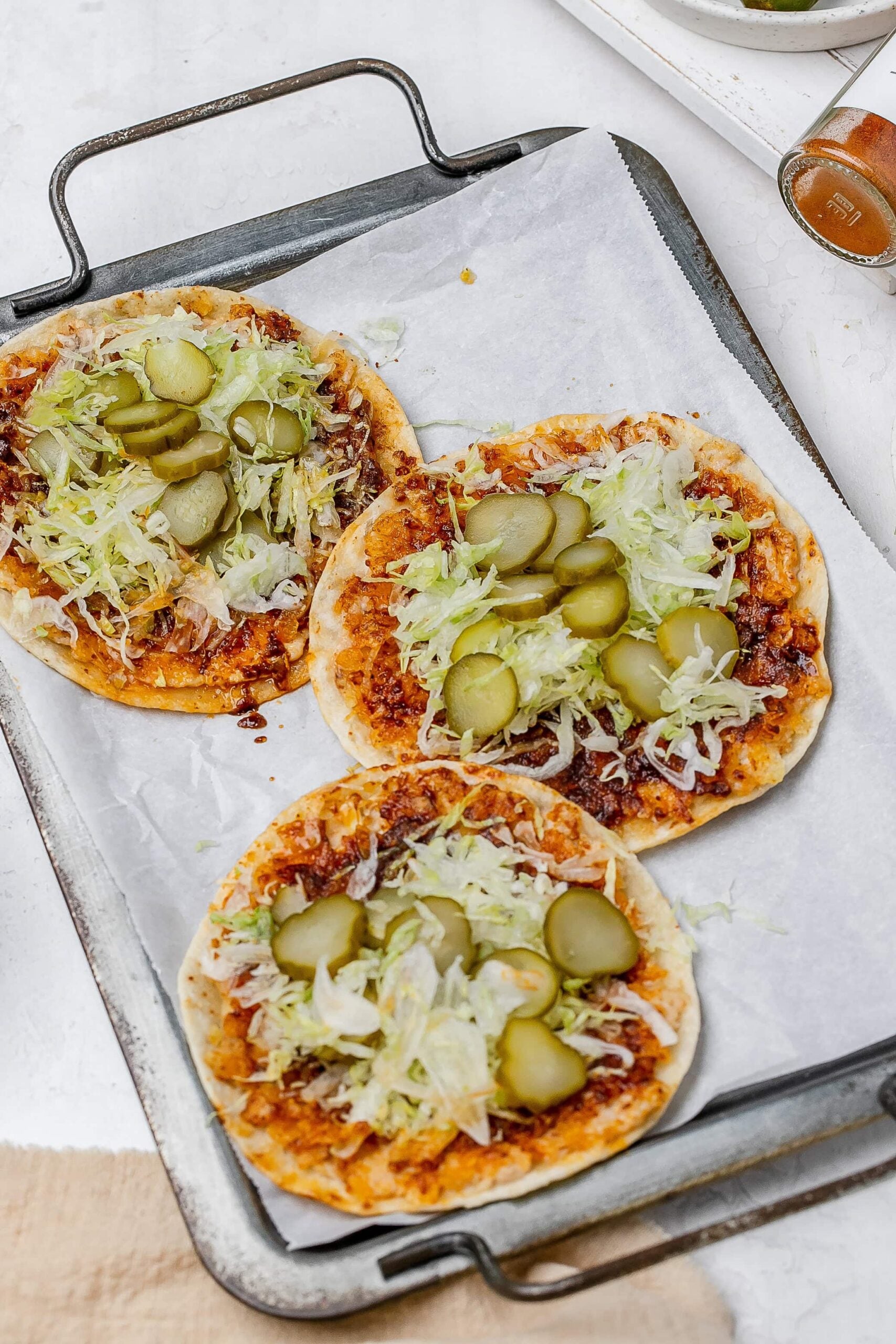 smashed Nashville hot chicken tacos on a baking sheet with toppings.