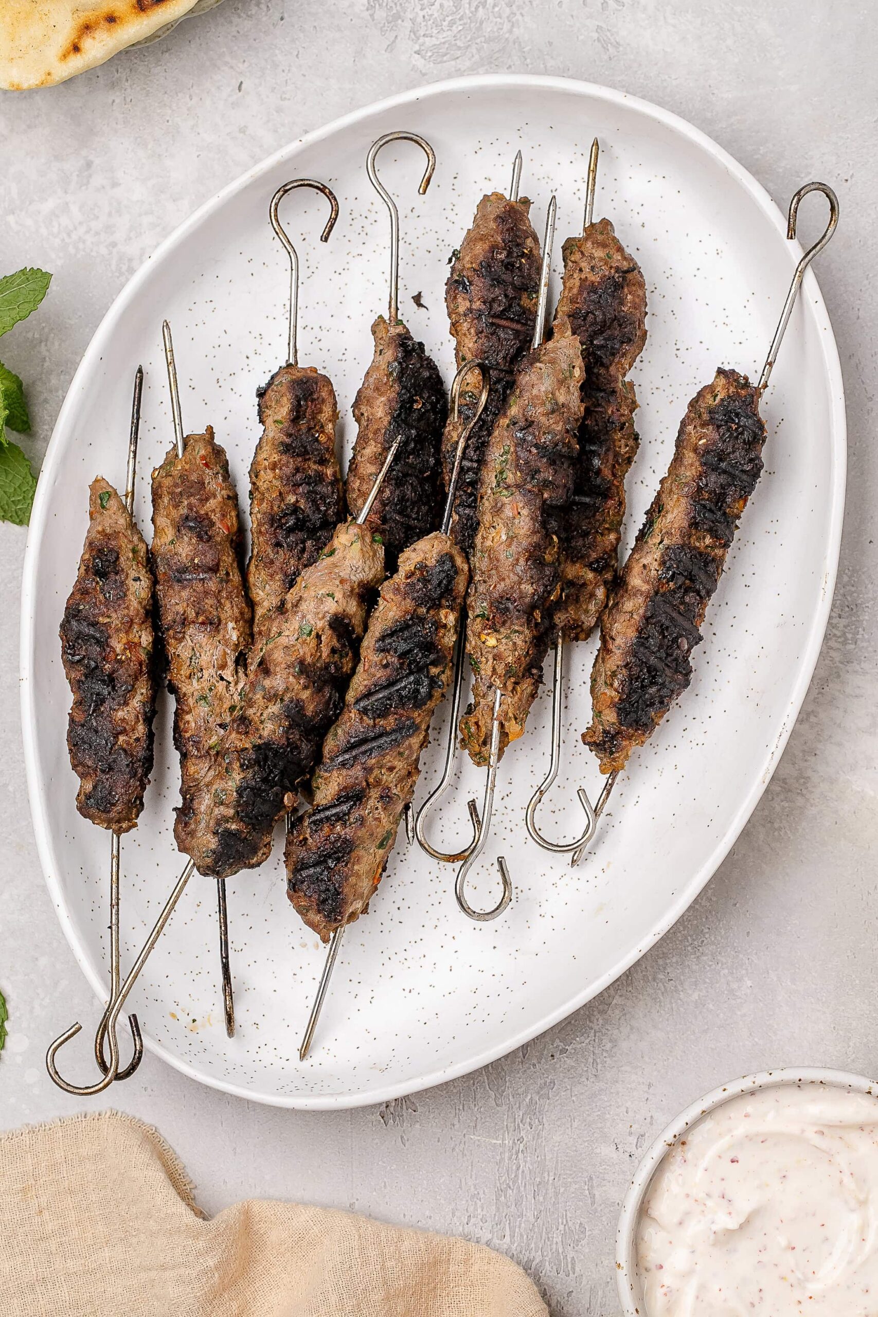 beef and lamb kofta skewers on a pita with toppings.