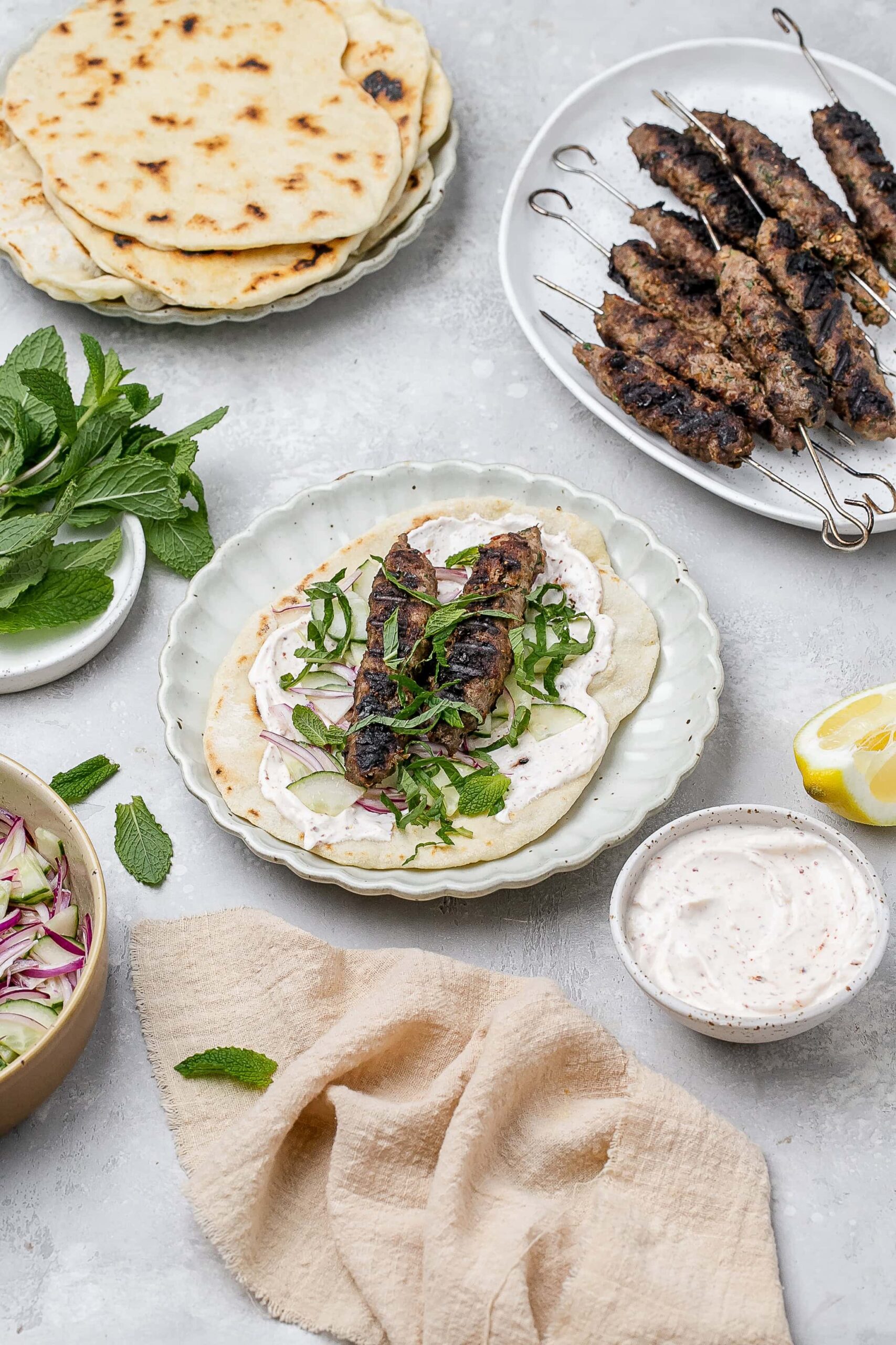 beef and lamb kofta skewers on a pita with toppings.