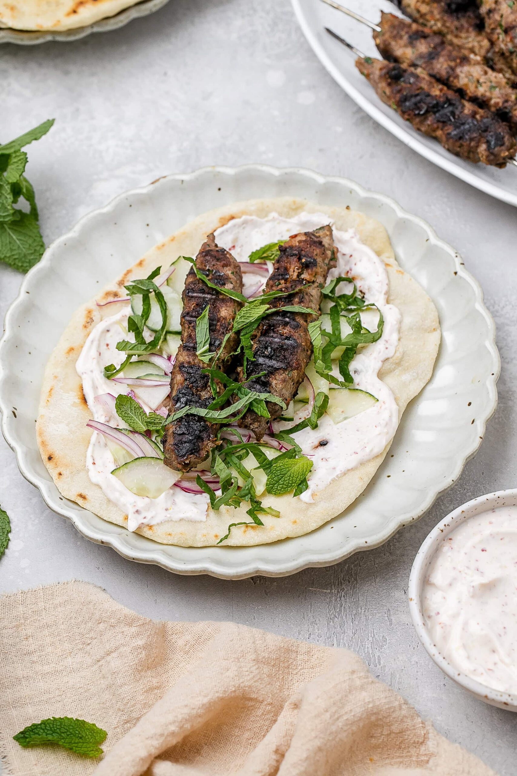 beef and lamb kofta skewers on a pita with toppings.