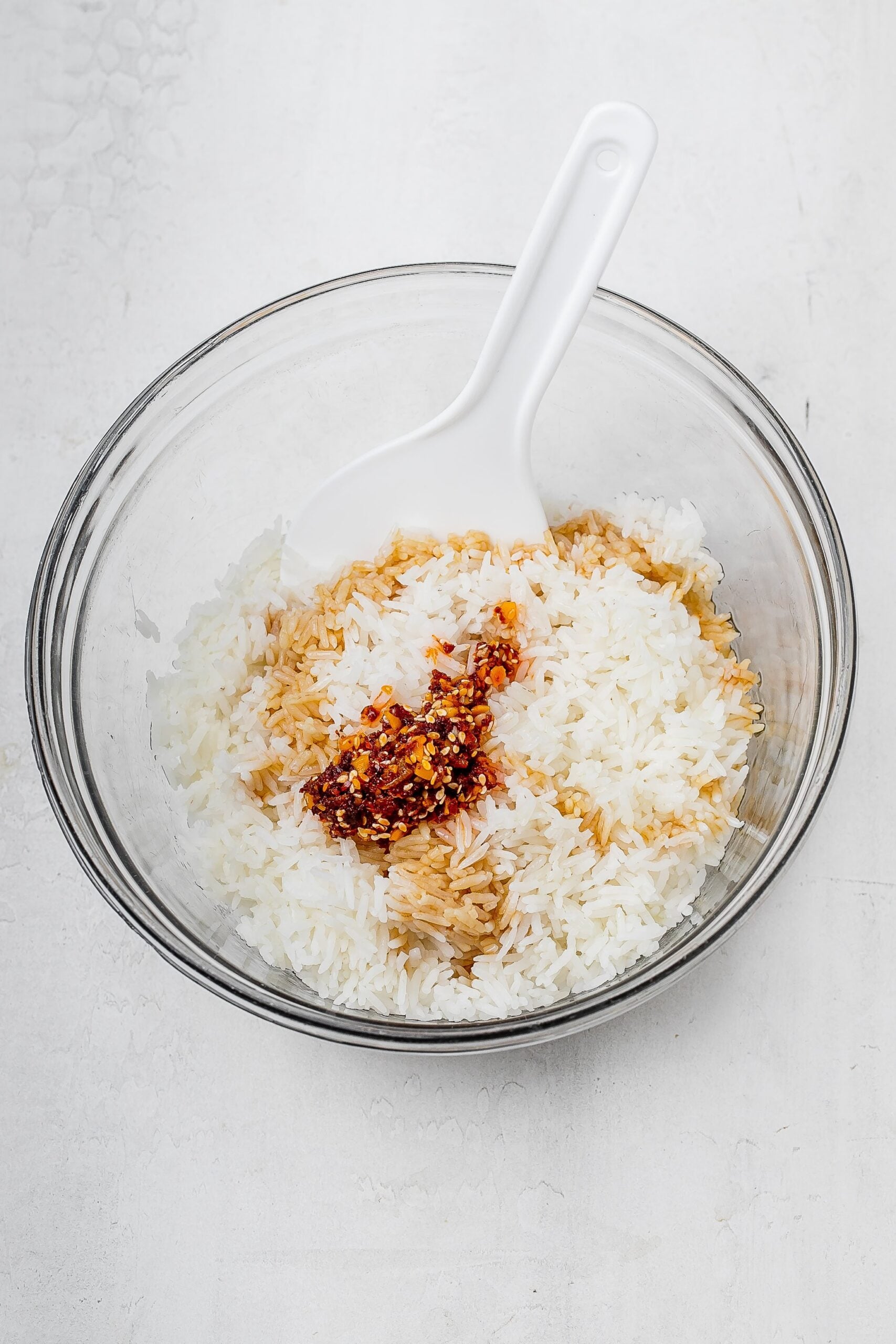 cooked rice in a bowl with chili crisp, oil and tamari.
