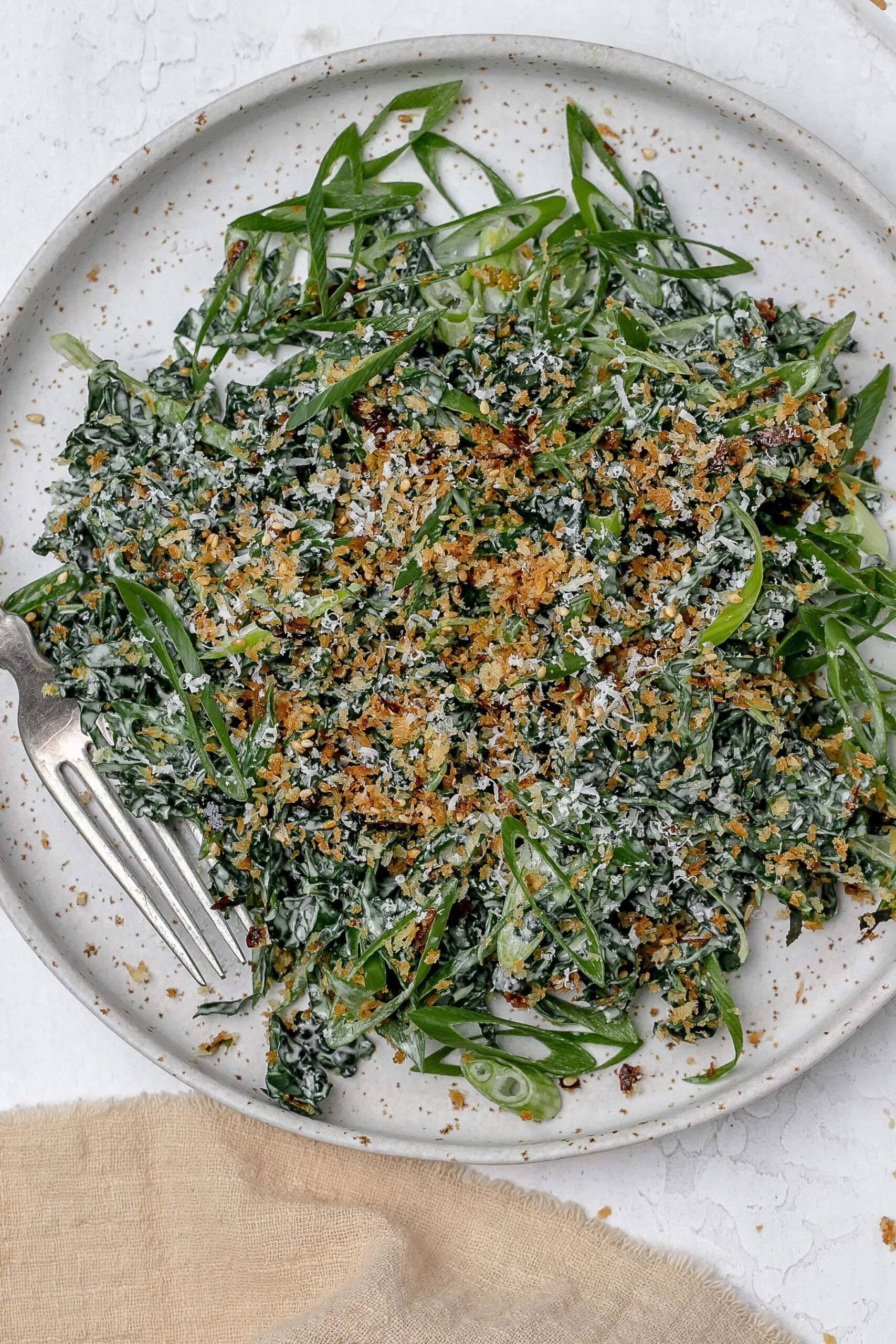 Miso kale caesar salad on a plate with a fork. 
