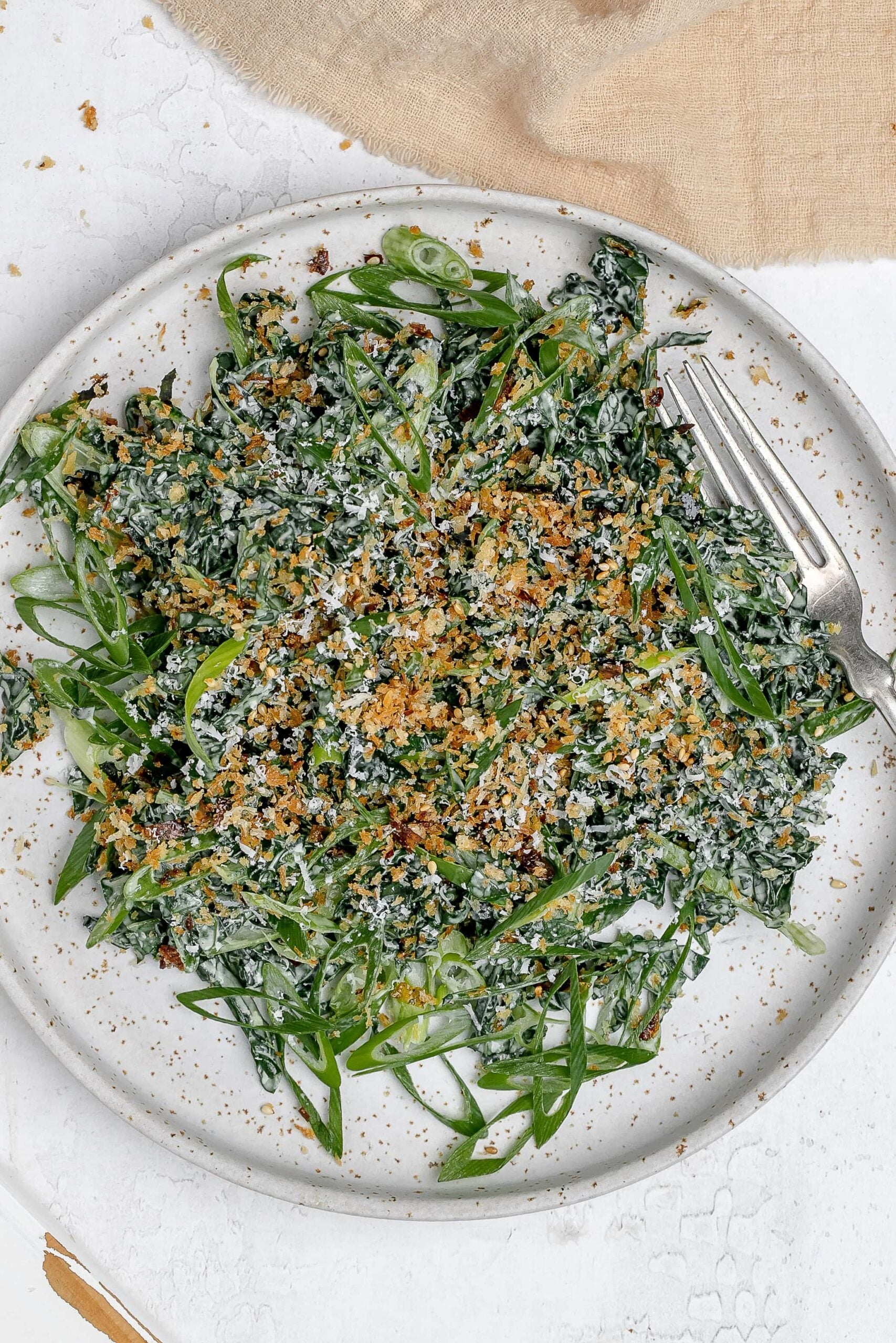 Miso kale caesar salad on a plate with a fork. 