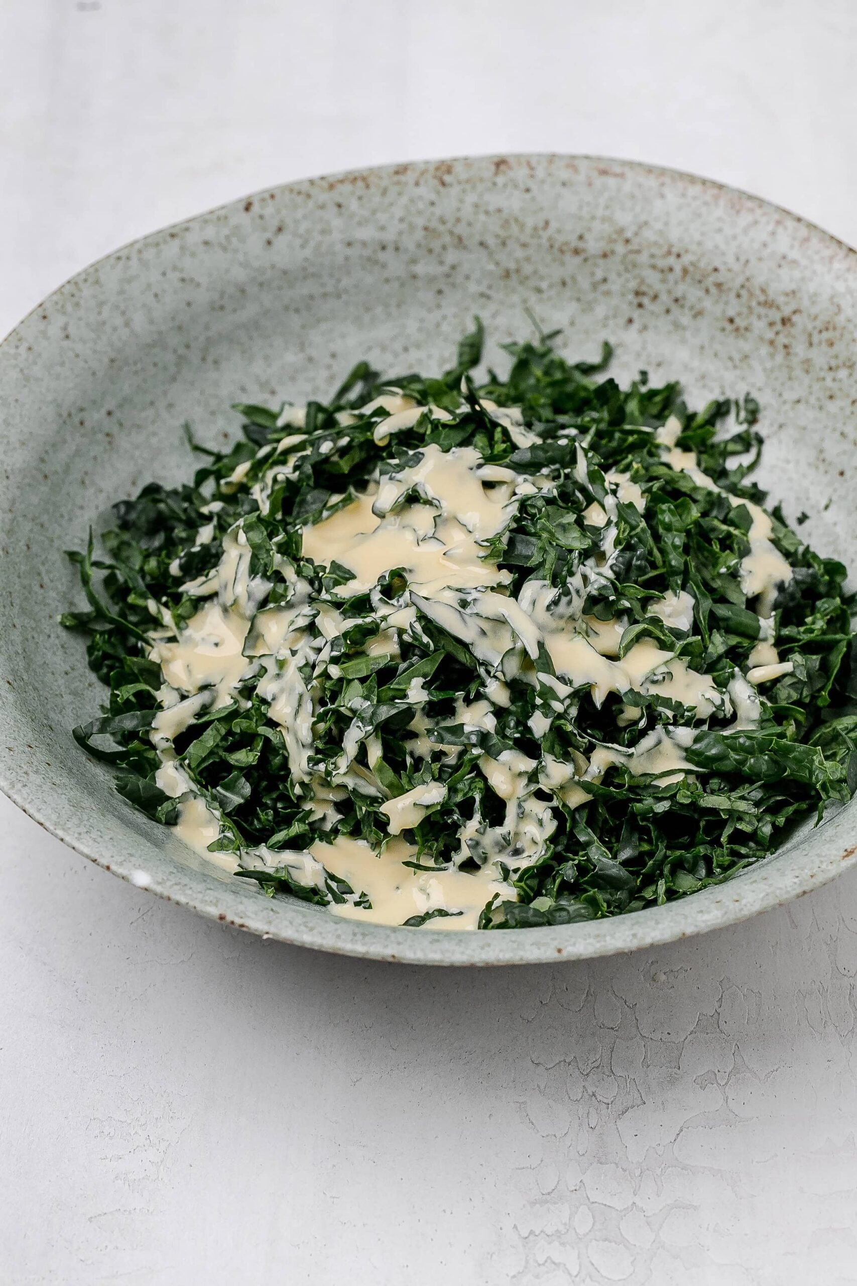 kale in a bowl with dressing drizzled on top. 