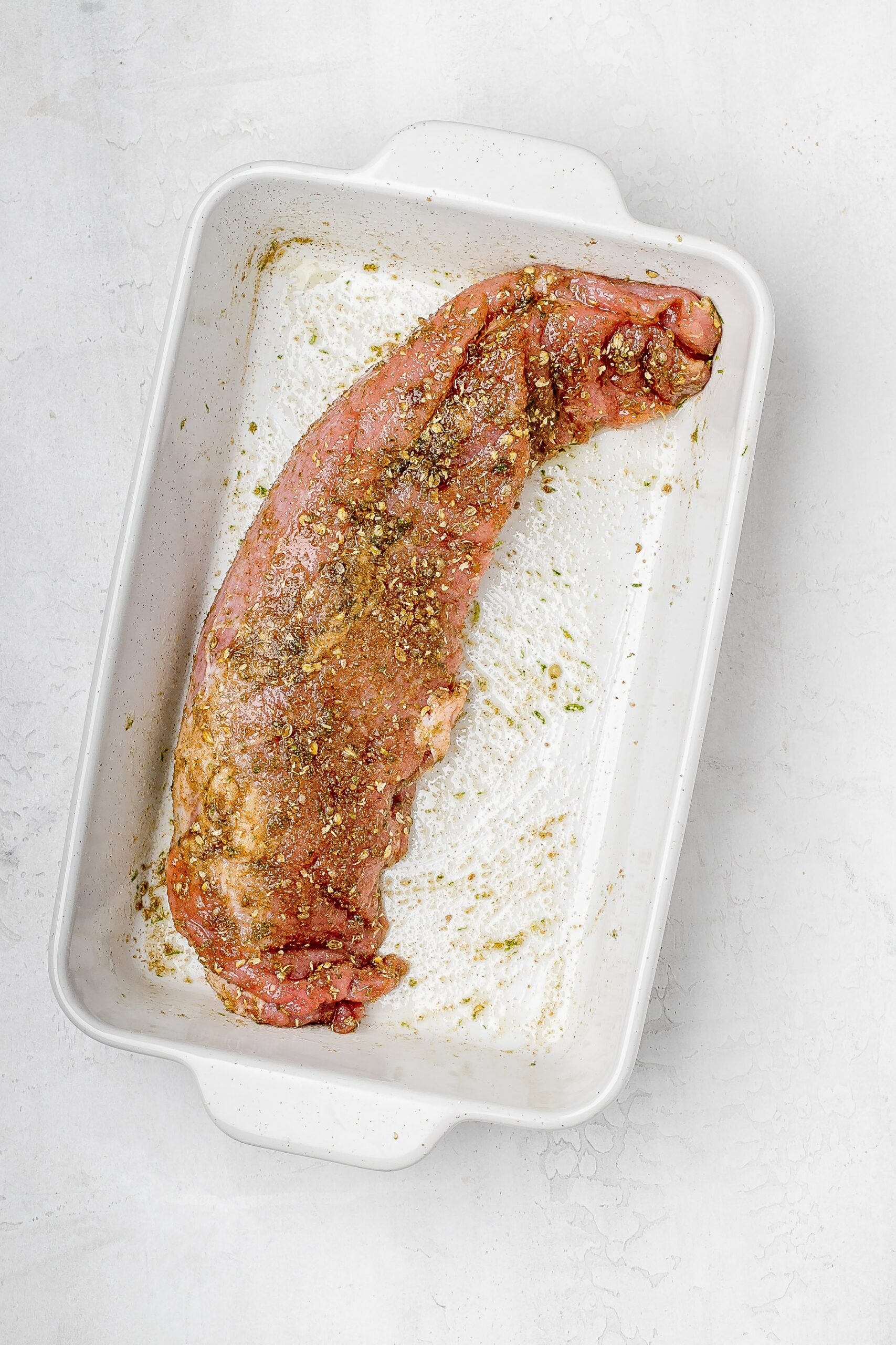 pork tenderloin in a baking dish with dry rub.