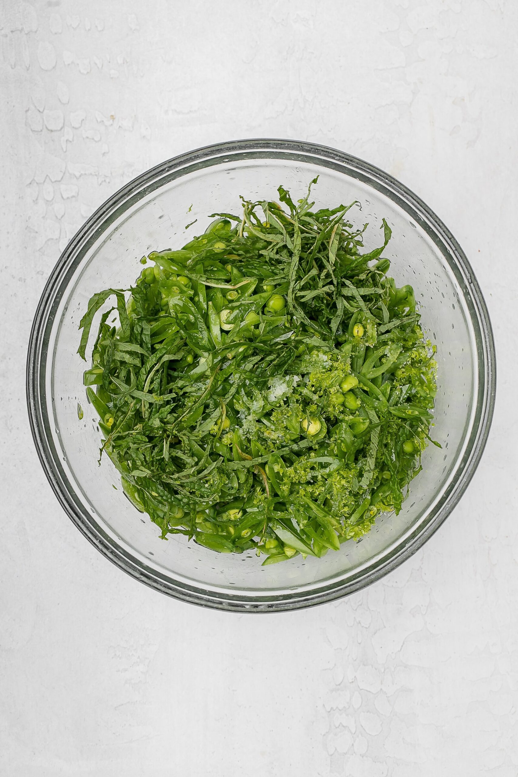 snap peas sliced thinly on a bias in a bowl with dressing.