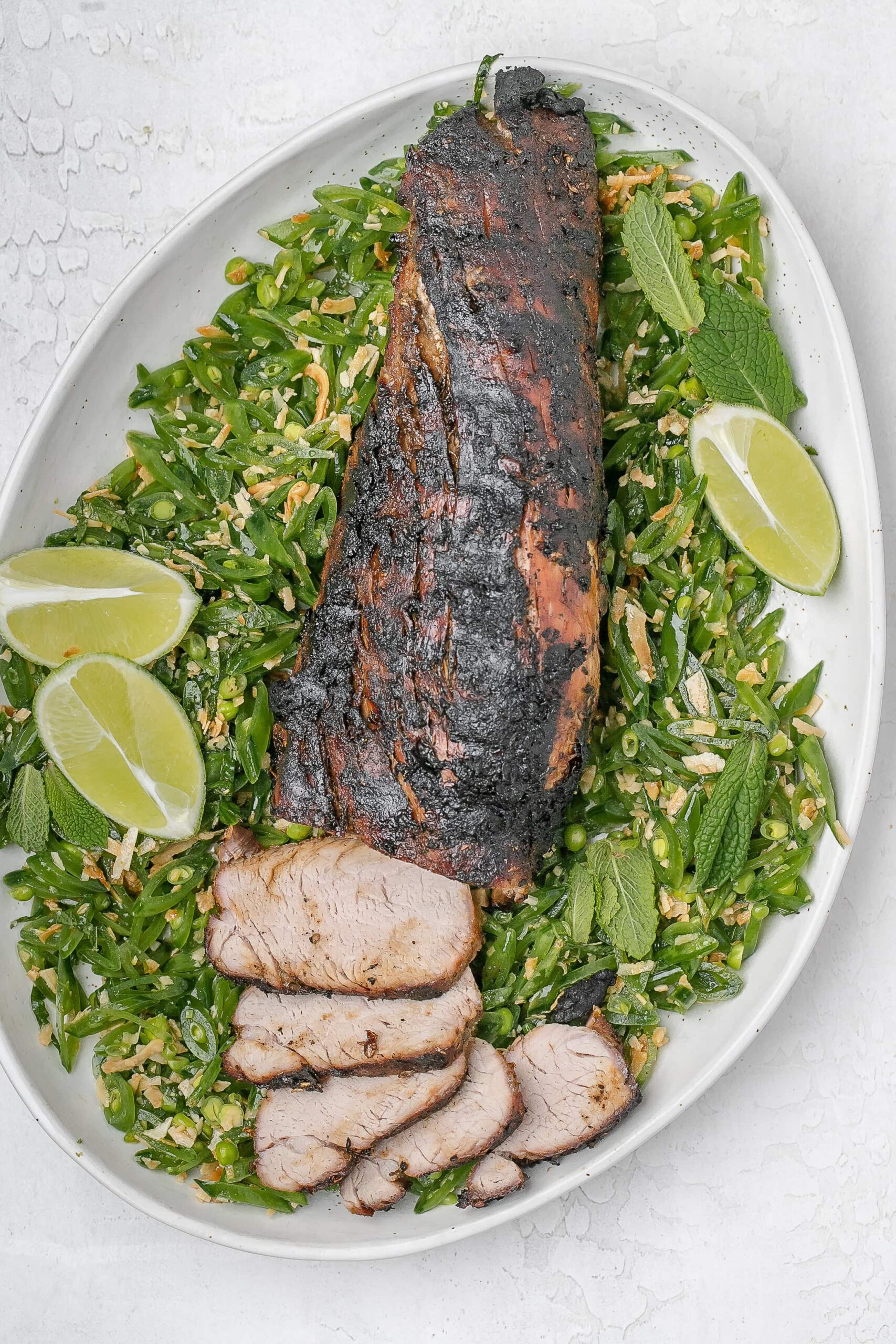 grilled pork tenderloin with peas surrounding it.