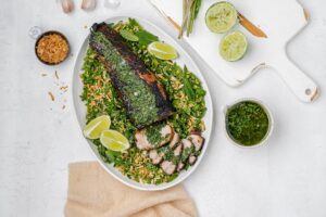 grilled pork tenderloin with chimichurri on top and peas surrounding it.