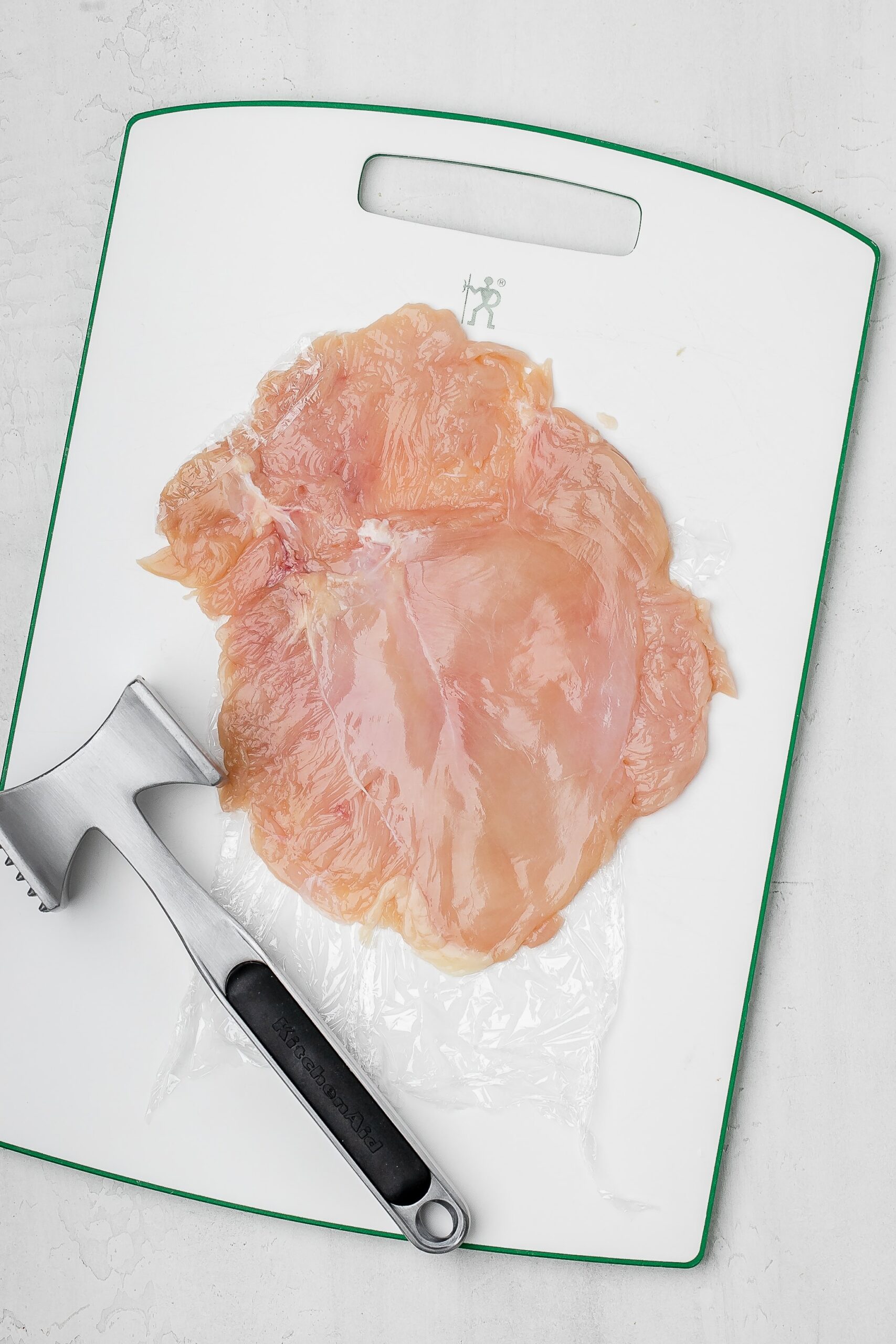chicken breast pounded thin on a cutting board.