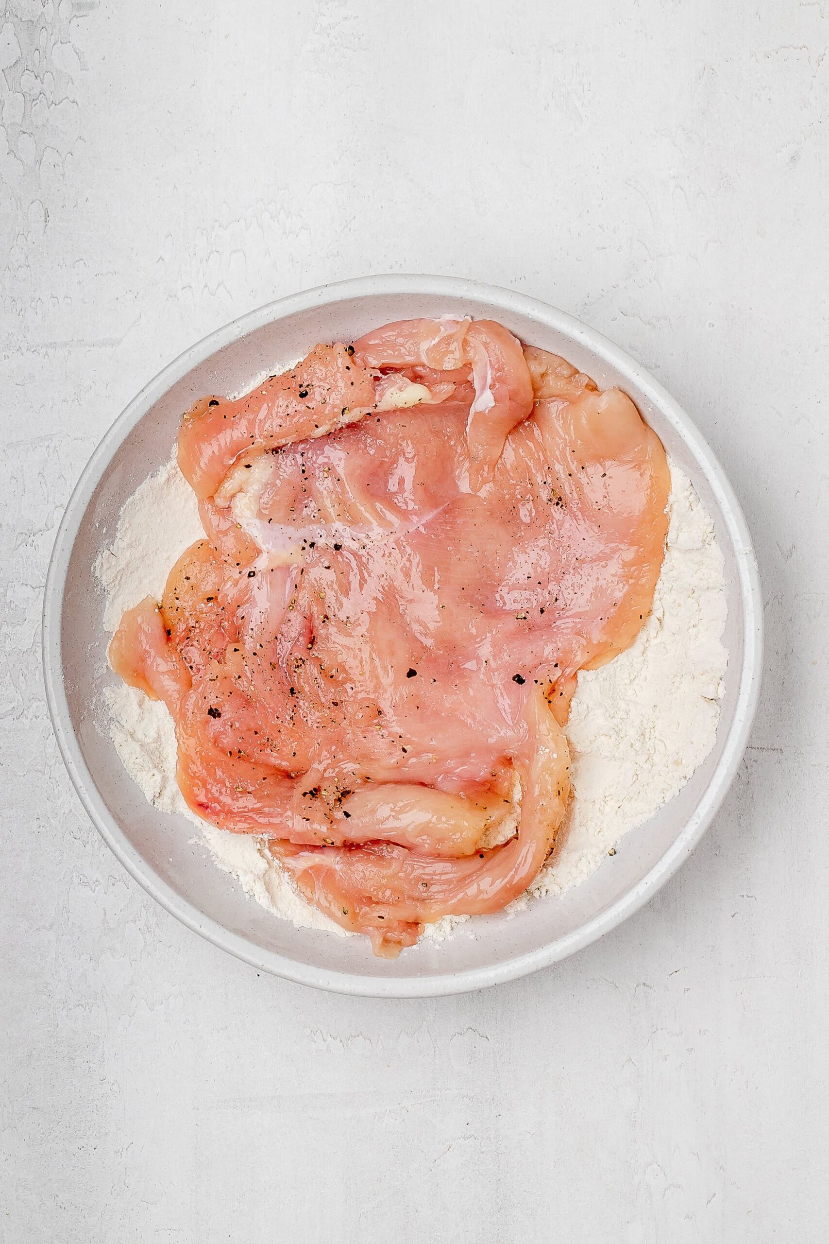flattened chicken coated in flour.