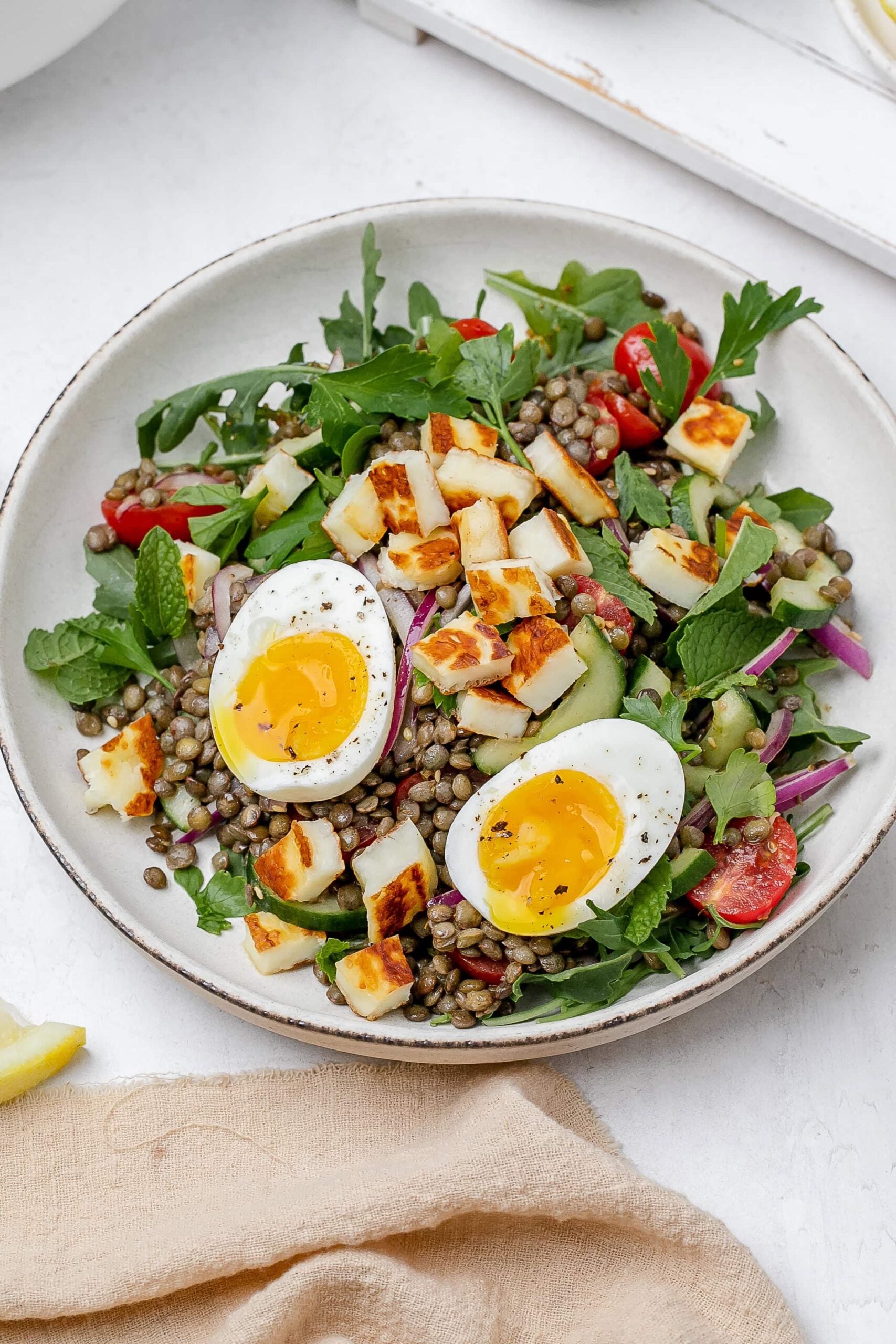 halloumi lentil salad in a bowl with a soft boiled egg on top.