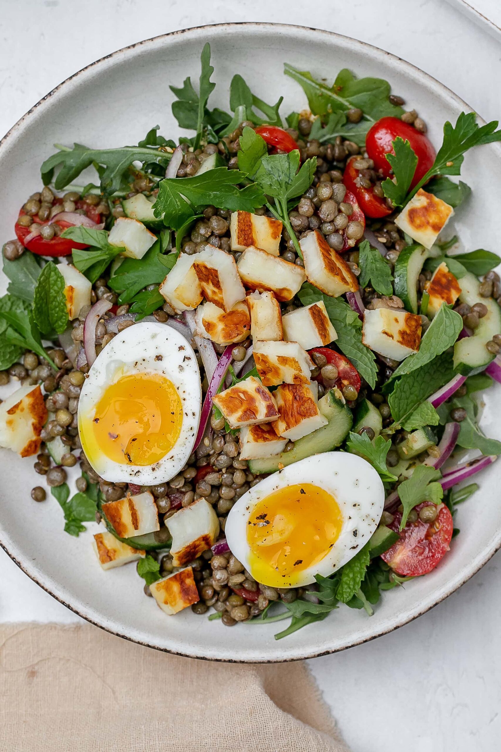halloumi lentil salad in a bowl with a soft boiled egg on top.