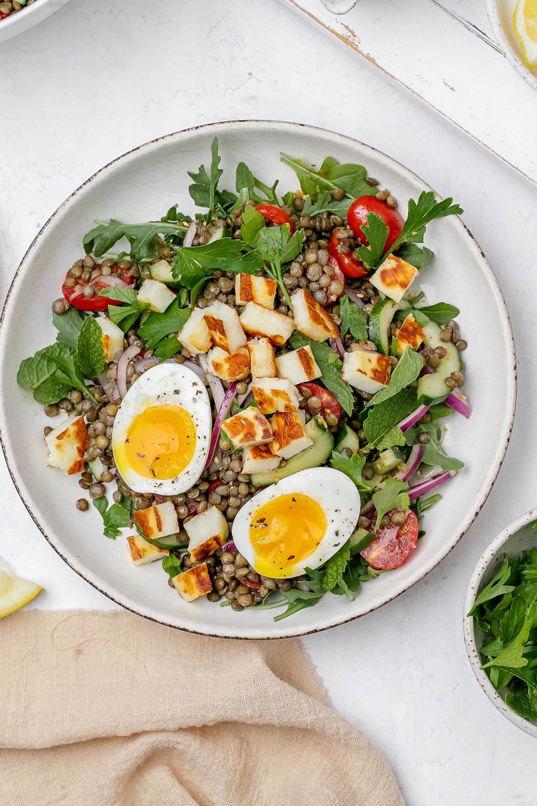 halloumi lentil salad in a bowl with a soft boiled egg on top.