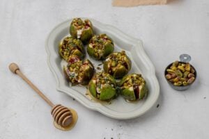 figs in baking dish stuffed with goat cheese and topped with pistachios.