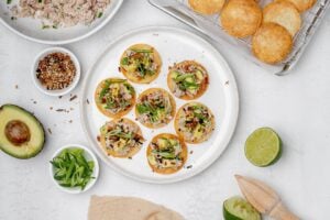 mini tuna tostadas on a plate topped with avocado.