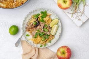 braised miso pork shoulder with cabbage and apples served over rice on a plate.