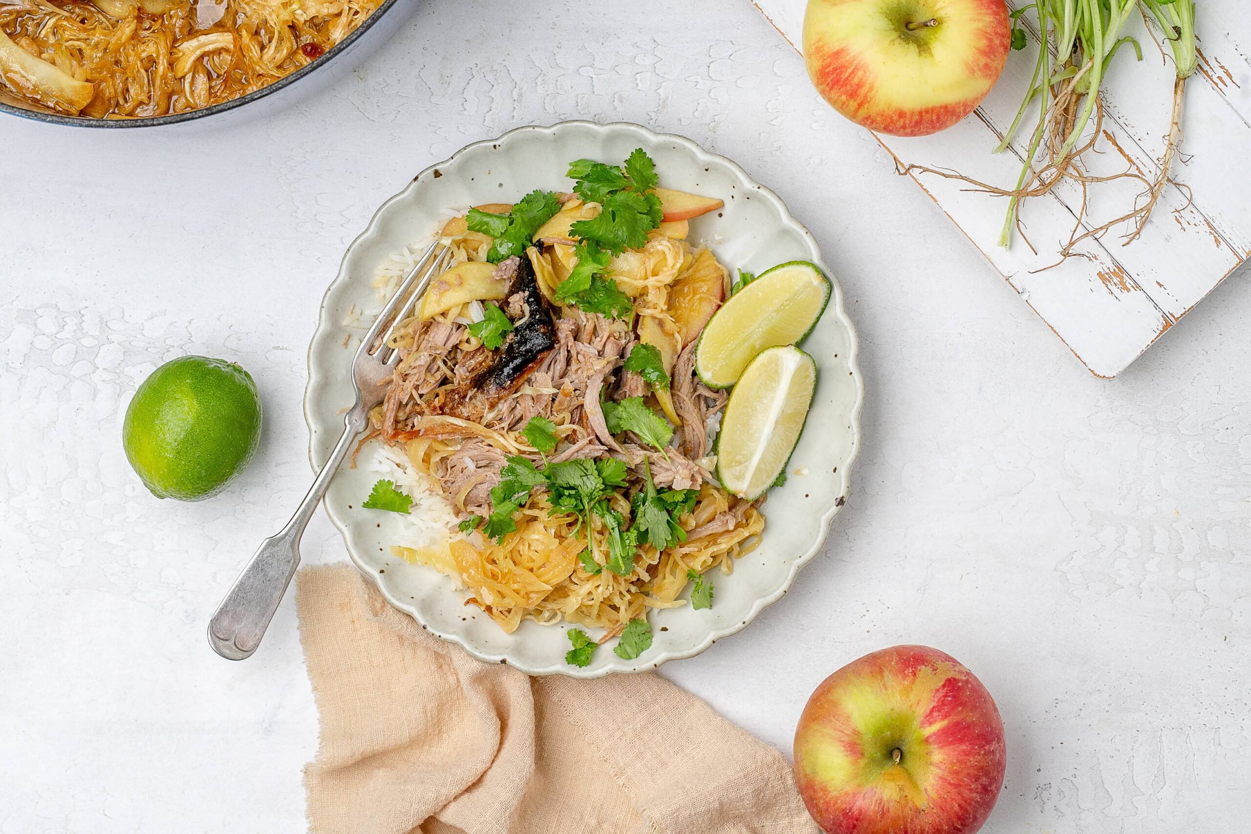 braised miso pork shoulder with cabbage and apples served over rice on a plate.