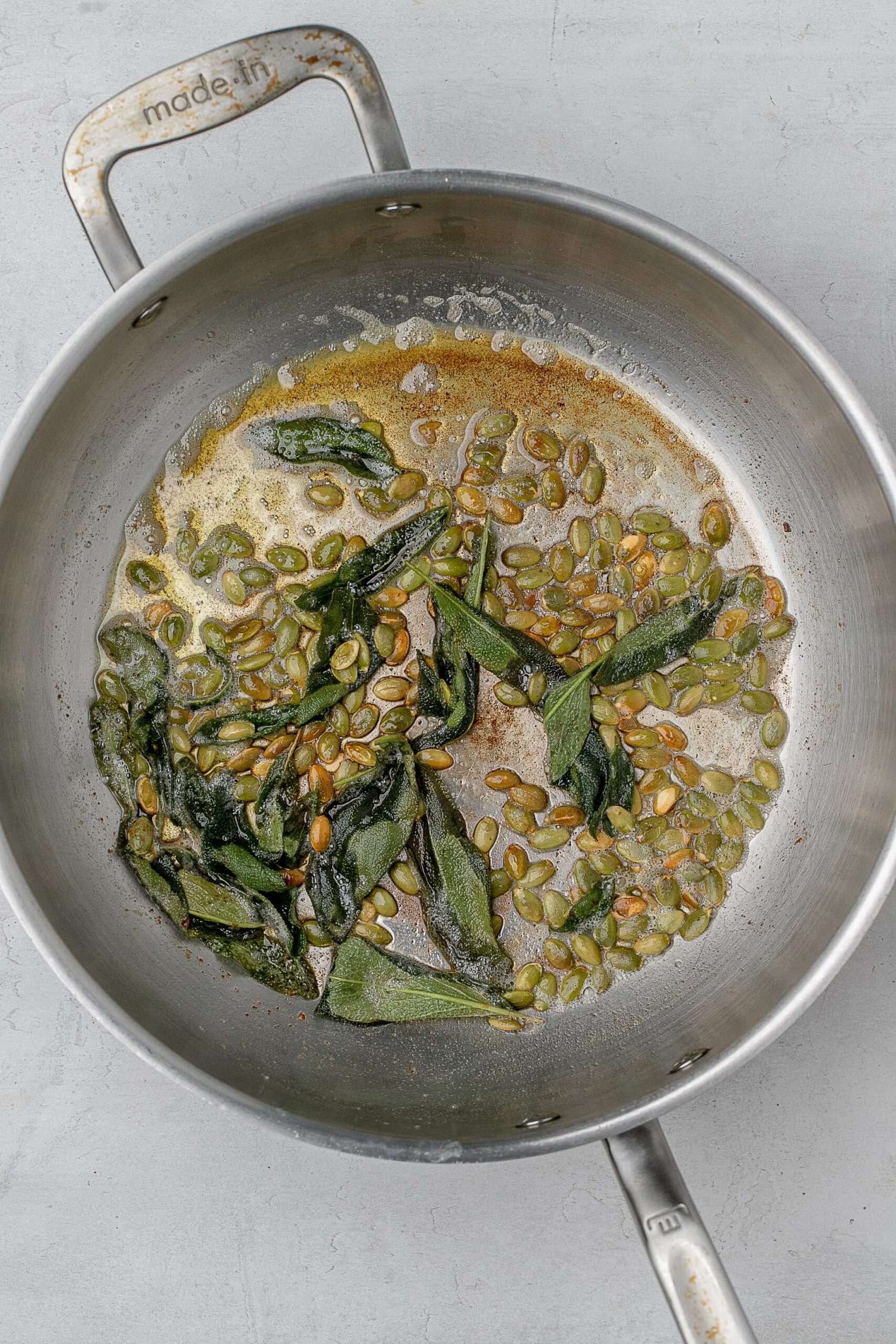 brown butter in pan with pumpkin seeds and sage.