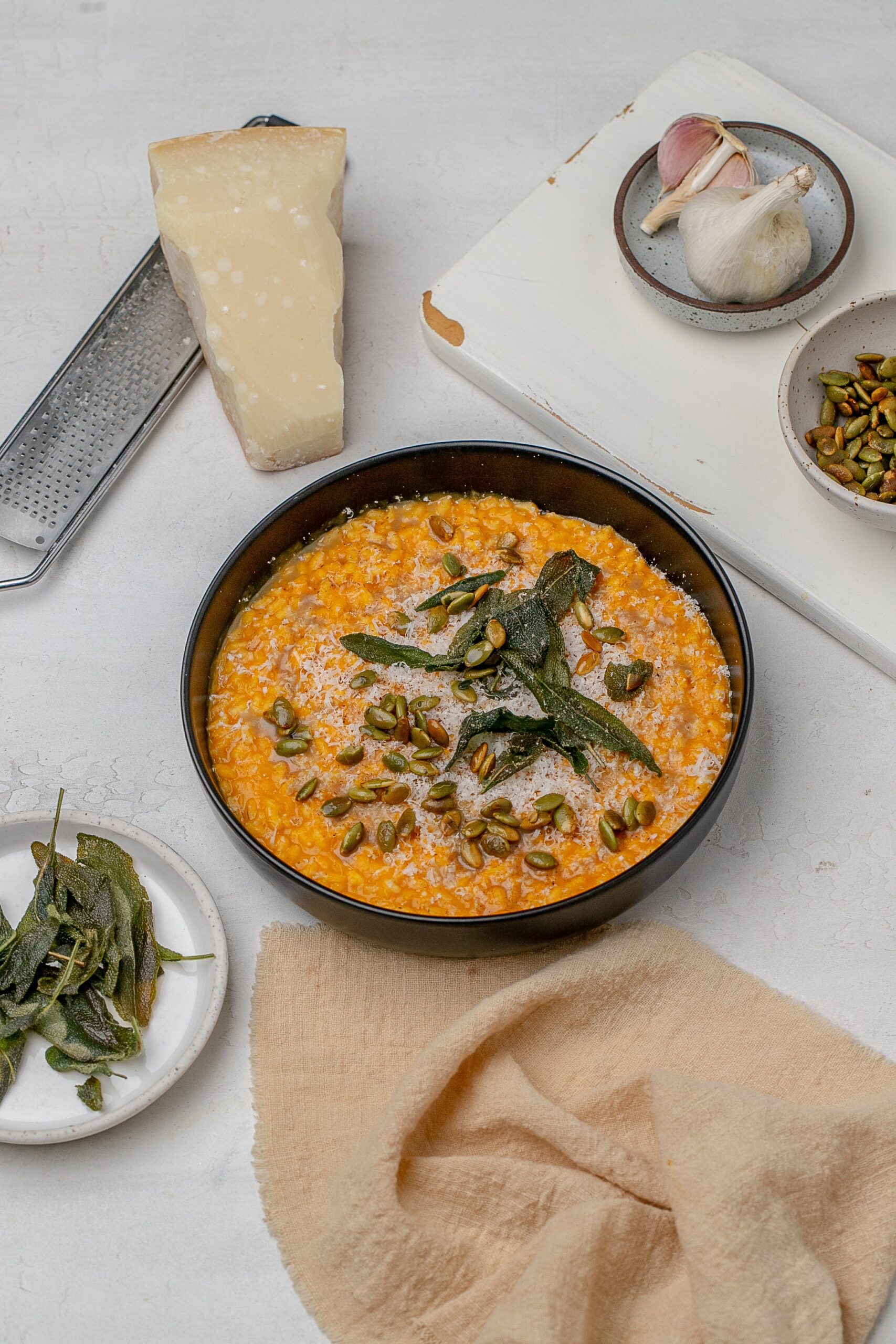 pumpkin risotto in a shallow black bowl with crispy sage, brown butter and pumpkin seeds.